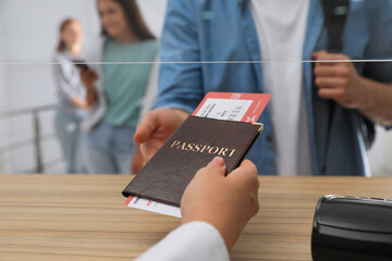 Agent giving passport with ticket to client at check-in desk in airport, closeup