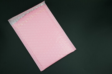 Pink padded envelope with bubble wrap on a black background