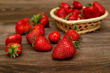 Ripe strawberries in a heart-shaped basket on a wooden table