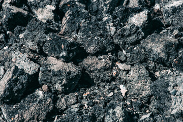 Repair of the road surface. A pile of stones made of old asphalt lies on the road. Textured abstract background. Close-up