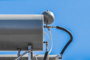 Water boiler heater tank system and hot technology on the roof of the house against the blue sky