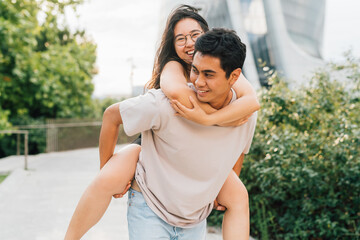 Fototapeta premium Young asian couple hugging outdoor riding piggyback smiling joyful in love
