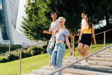 Naklejka premium Group of young multiethic people friends walking outdoor chatting and enjoying togetherness and good company