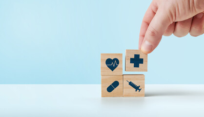 Health insurance concept, hand holding a wooden cube with medical health icons.