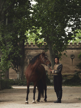 African American woman with horse near building and trees