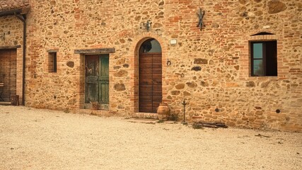 The facade of a rural stone farmhouse with wooden doors and windows in the italian countryside (Tuscany, Italy, Europe)