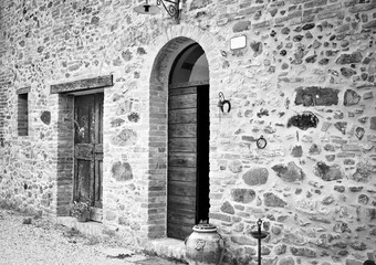 The facade of a rural stone farmhouse with wooden doors and windows in the italian countryside (Tuscany, Italy, Europe)