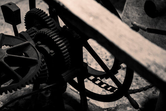 close up pof an antique traditional olive press with low light and focus techniques
the gears out of steal and the meal stone our of granite 