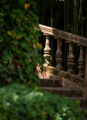 rustic stairs in a wonderful garden with columns illuminated by the sun light which is breaking through the plants of the garden, romantic place to relax and inhale 