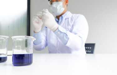 Science innovative Male medical or scientific laboratory researcher performs tests with blue liquid...