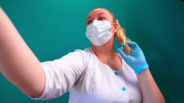 Female doctor taking silly selfies with smartphone. Yang blonde woman. Cosmetology concept.