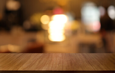 Naklejka na ściany i meble Empty wooden table in front of abstract blurred background of coffee shop . can be used for display or montage your products.Mock up for display of product
