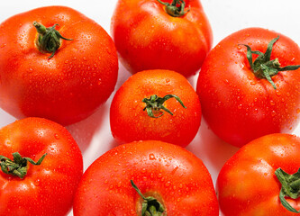 Red fresh tomatoes with water drops on a white background
