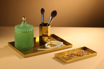 Gold trays for jewelry and decorations on beige background with light wall