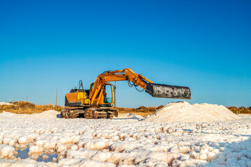 Obraz premium Sea salt harvest with yellow digger at salines in Faro, Portugal