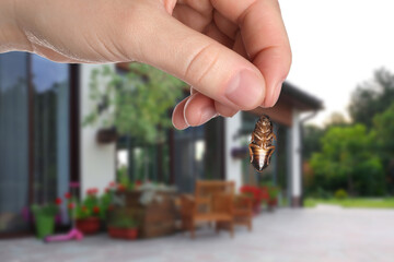 Woman holding dead cockroach and blurred view of modern house on background. Pest control