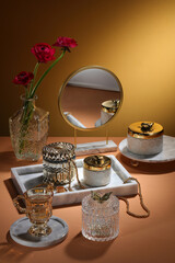 Concept table with mable tray and luxury jewelry jar and mirror, flower on beige background with light on the wall