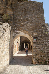 Fototapeta na wymiar Touriste femme promenant dans une ruelle pavée du village médiéval de Saint-Montan en Ardèche