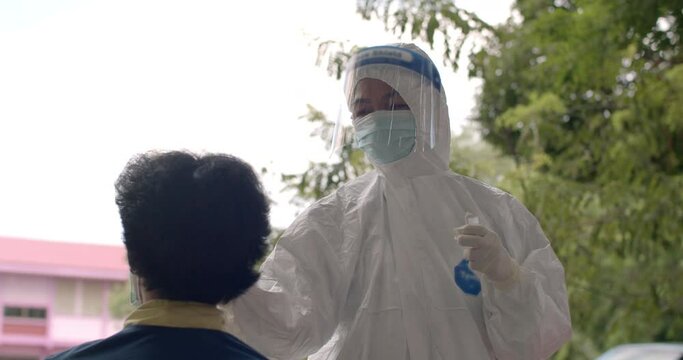 Slow motion of the mobile team of Asian doctors, nurses and staffs wearing PPE, mask, face shield are screening for COVID-19 at high-risk communities using Antigen Test Kid(ATK), nasal secretion swab.