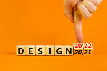 Planning 2022 design new year symbol. Businessman turns wooden cubes and changes words 'design 2021' to 'design 2022'. Beautiful orange background, copy space. Business, 2022 design new year concept.