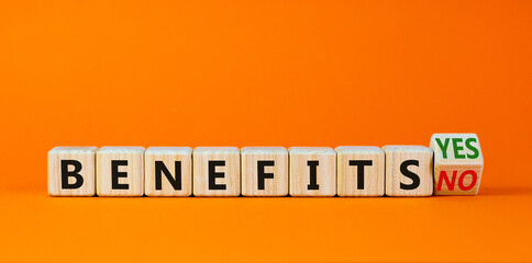 Benefits symbol. Turned a wooden cube and changed words 'benefits no' to 'benefits yes'. Beautiful orange background. Business and benefits concept, copy space.