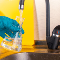 water purification specialist tap water pours into a glass flask.