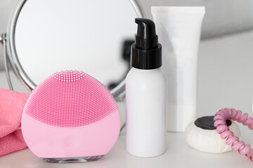 Pink cleanser device, cleanser mousse ,cleansing cloths and moisturizing cream on white table....