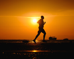 Silhouette of man running along the road during the sunset