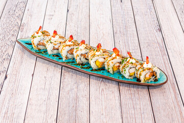 Sushi uramaki dragon roll with shrimp in tempura, pieces of ripe mango and Norwegian salmon with wasabi and ginseng