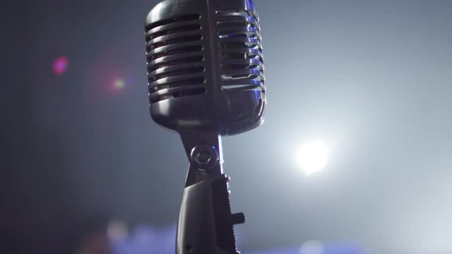 Few Shots Of Professional Concert Vintage Glare Microphone For Record Or Speak To Audience On Stage In Dark Empty Retro Club Close Up.  Vintage Microphone Against A Dark Background With Spotlight