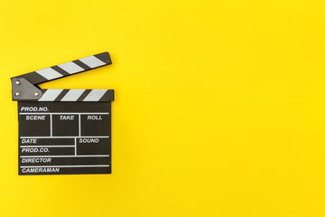 Naklejka premium Filmmaker profession. Classic director empty film making clapperboard or movie slate isolated on yellow background. Video production film cinema industry concept. Flat lay top view copy space mock up.