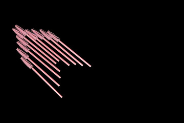Pink eyelash brushes on a black background. Cosmetic accessories for eyelash extensions
