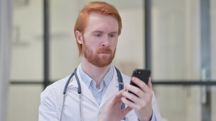 Obraz na płótnie Canvas Redhead Male Doctor using Smartphone at Work 