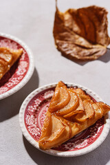 Slices of Homemade French Apple Tart or Pie on plates on light concrete background