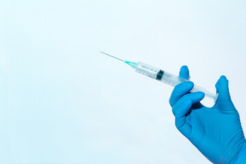 hand with blue gloves holding a syringe