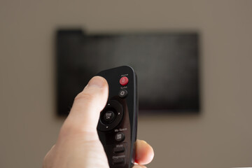 a man turns on the TV holding the remote in front of him. copy space.