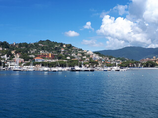 High angle shot of a bay with small ships in blue waters and urban setting on the seashore © Ingrid Paquot/Wirestock