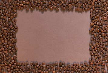 A coffee frame with a copyspace. A top down shot of coffee beans on a pink surface on a brown...