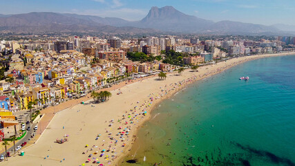 Fototapeta na wymiar Tomas cenitales y aéreas de la ciudad y la playa de Villajoyosa en Alicante con gente tomando el sol con sus sombrillas y bañandose en el mar