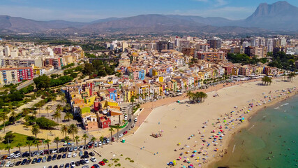 Obraz premium Tomas cenitales y aéreas de la ciudad y la playa de Villajoyosa en Alicante con gente tomando el sol con sus sombrillas y bañandose en el mar