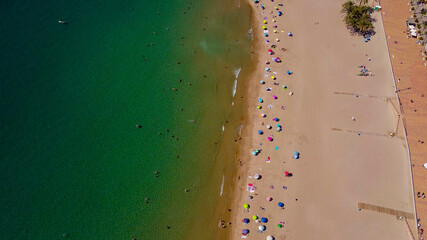 Fototapeta na wymiar Tomas cenitales y aéreas de la ciudad y la playa de Villajoyosa en Alicante con gente tomando el sol con sus sombrillas y bañándose en el mar