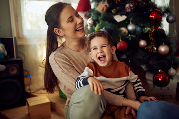 Joyful boy has fun with his mother on Christmas day at home.