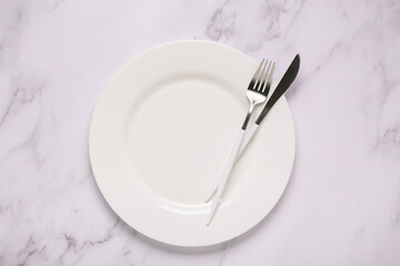 Clean empty white plate with cutlery.
