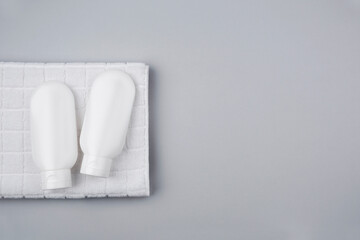 Two plastic white tubes for cream or lotion on the background of a white towel. Top view on grey background. Skincare natural cosmetic