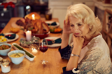 Sad mature woman feels lonely and missing her family at dining table on Thanksgiving.