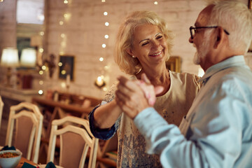 Romantic senior couple enjoys while dancing on Christmas Eve at home.