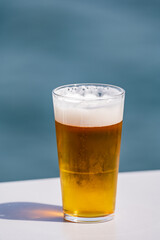 Glass of draught beer served outdoor on terrace with sea view