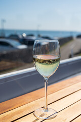 Glass of white wine served on outdoor terrase with seaview, summer vacation