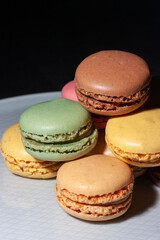 Macarons de colores sobre fondo negro. Concepto gastronomía repostería. 
