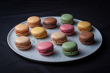 Macarons de colores sobre fondo negro. Concepto gastronomía repostería. 